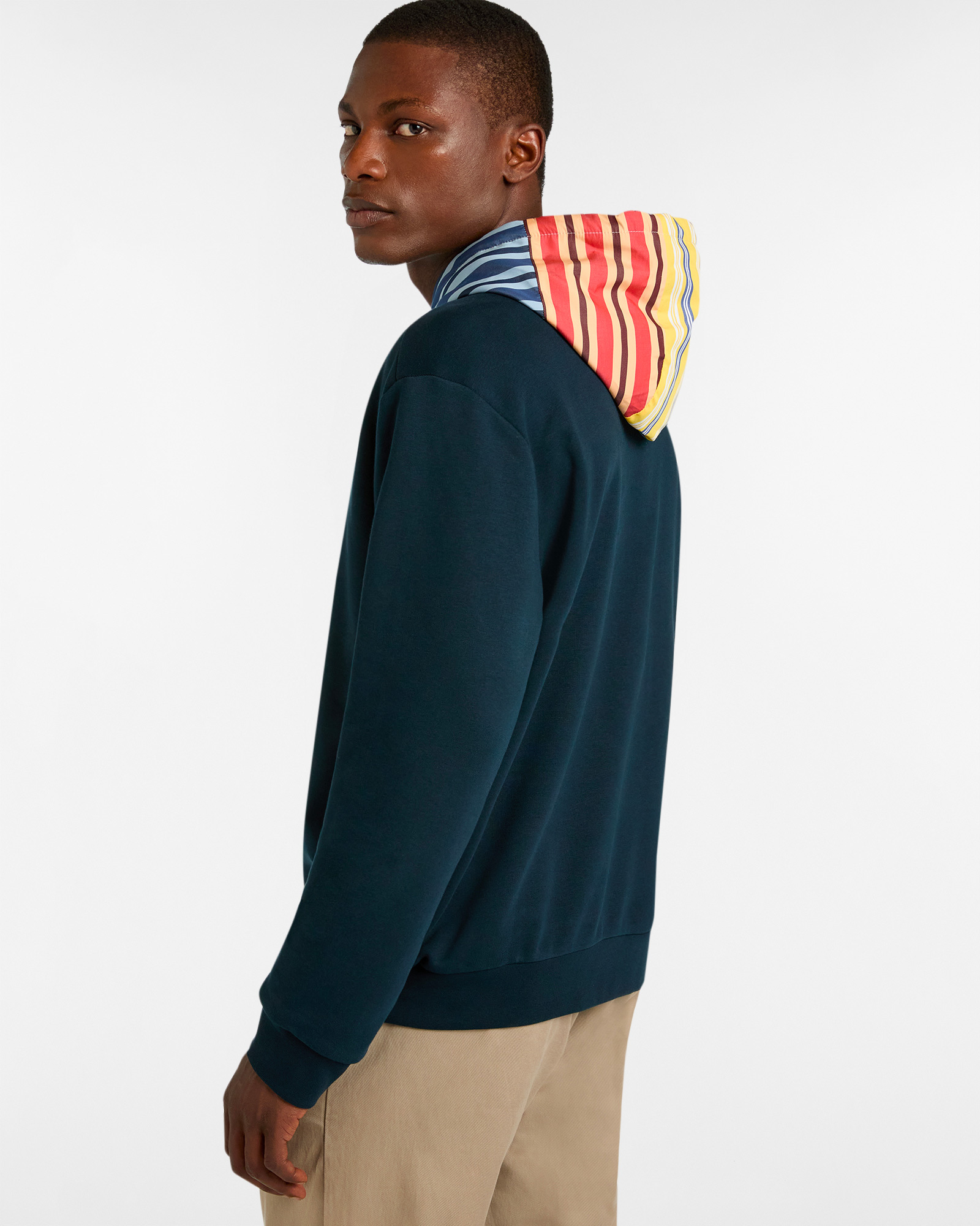 Man in dark blue sweatshirt with multicolored striped hood